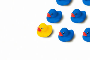 yellow duck standing out from crowd of blue ducks. euphemism for digital marketing strategies 